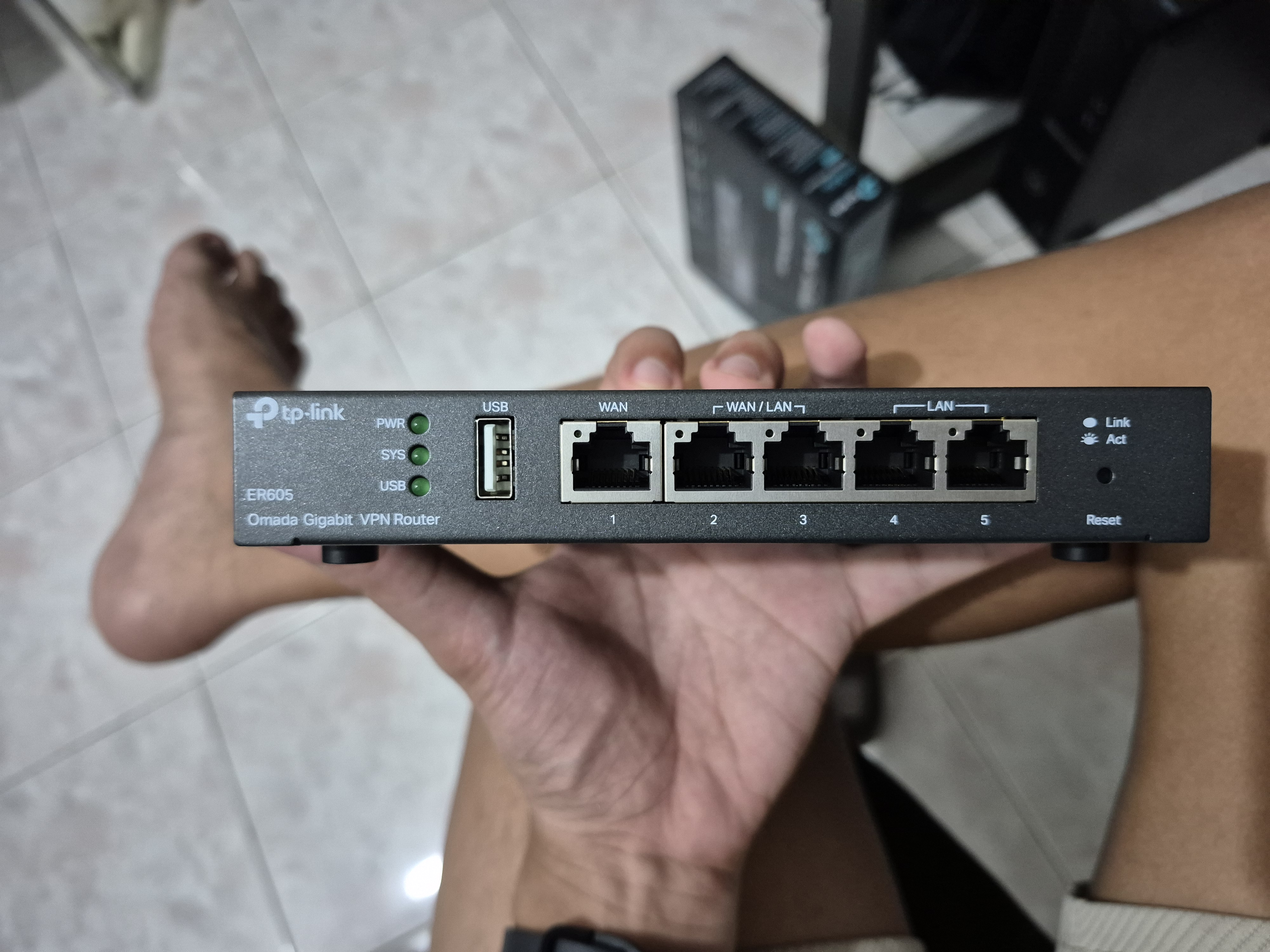 A TP-Link ER605 Omada router being held up for a photo — the upgrade that retired the ISP one.